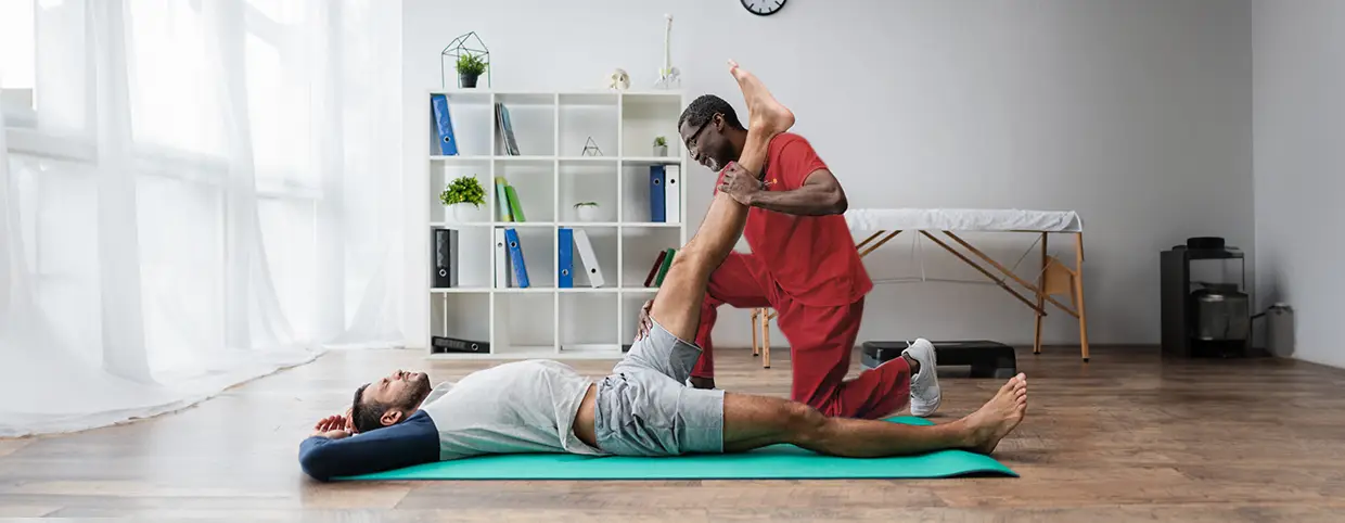 Sports physiotherapist treating a person lying on a mat