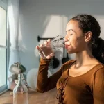 A young girl drinking water to get rid of the flu